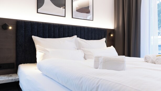 A neatly made bed with white linens and pillows, a dark headboard, and a bedside table with a marble top. - BRIGHT Schloß Holte-Stukenbrock (Schloss Holte-Stukenbrock)
