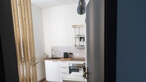 A modern kitchen with white cabinets, a wooden countertop, and a hanging light fixture. - DLG-STAYS - "Pure 23" (Iserlohn)