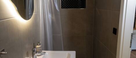A modern bathroom with a shower, a sink, and a mirror.