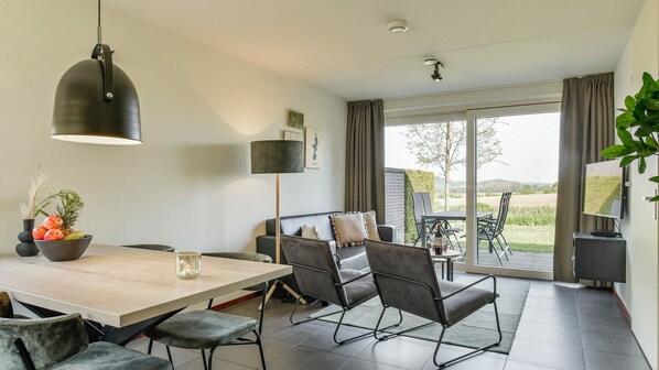 A modern dining area with a wooden table, grey upholstered chairs, and a pendant light.