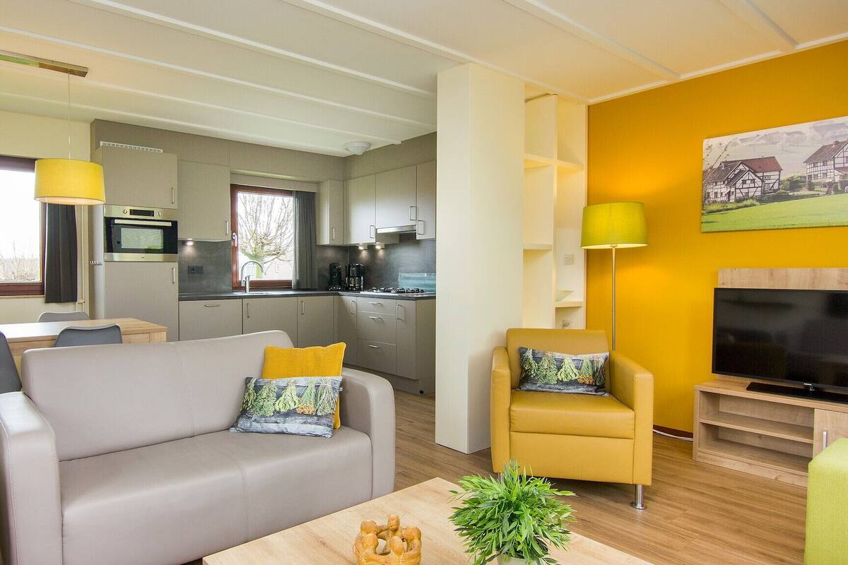 A modern living room with a sofa, armchairs, a coffee table, and a TV.