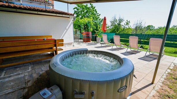 Un espace extérieur aménagé avec un jacuzzi, un banc et des chaises longues.