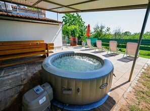 Un espace extérieur aménagé avec un jacuzzi, un banc et des chaises longues.