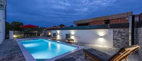 Una piscina al aire libre, sombrillas, sillones reclinables de piscina