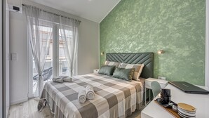 A modern bedroom with a checkered bedspread, a green textured wall, and a laptop on the bedside table. - Peaceful Blooming Villa With Pool (Rovinj)