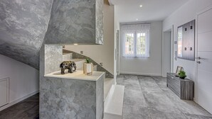 A modern interior with a stone accent wall, a staircase, and a view of the outdoors. - Peaceful Blooming Villa With Pool (Rovinj)