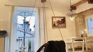 A dining area with a chandelier, a painting, and a view of buildings through a window. - Enchanting Quiet Residence Rovinj Downtown (Rovinj)