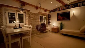 A cozy living room with a stone wall, a dining table with chairs, a sofa, a bookshelf, and a painting on the wall. - Enchanting Quiet Residence Rovinj Downtown (Rovinj)