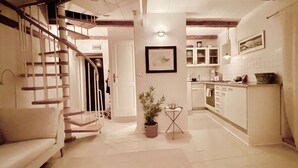 A spacious living area with a staircase, a dining table, and a kitchen area with cabinets and a countertop. - Enchanting Quiet Residence Rovinj Downtown (Rovinj)
