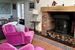Relax by the fireplace in this inviting living room featuring a comfortable sofa, brick hearth, and dining area.