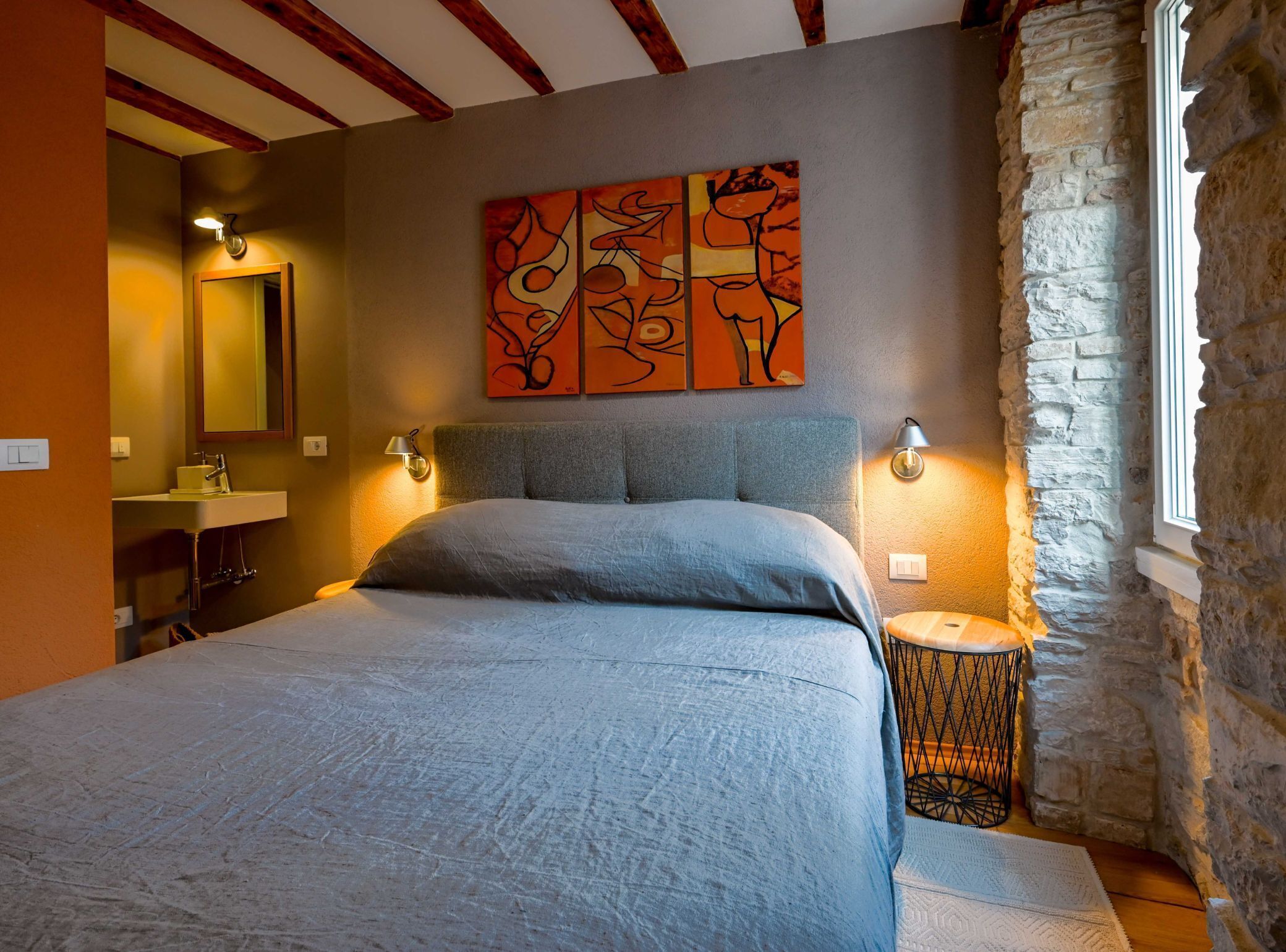 Ein Schlafzimmer mit einem Bett, einem Nachttisch, einem Spiegel und einem Bild an der Wand.
