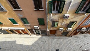 A view of a narrow street with buildings on either side, featuring multiple windows with shutters, air conditioning units, and a paved sidewalk. - Alluring Studio Apartment Downtown Rovinj (Rovinj)