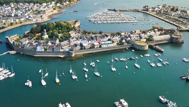 A coastal town with a fortified harbor, numerous boats, and a mix of residential and commercial buildings. - Charming seaside house (Concarneau)