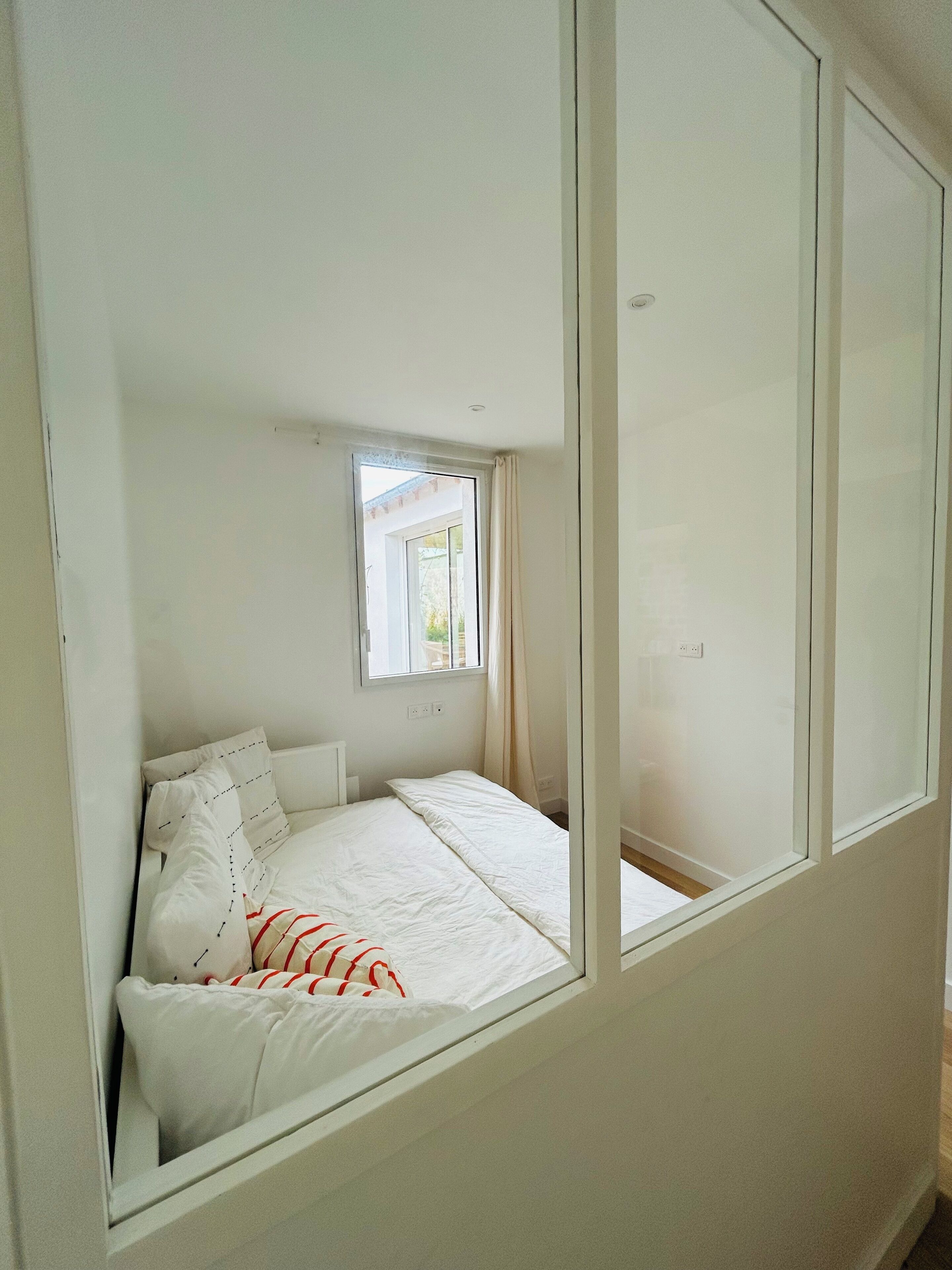 A bedroom with a bed, a window, and a view of the outside.