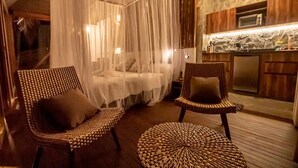 A cozy room with a canopy bed, wicker furniture, and a kitchenette. - Cozy Cabin Nestled in Bamboo Forest (El Caimo)