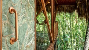 A wooden structure with a stone wall and a metal handle. - Cozy Cabin Nestled in Bamboo Forest (El Caimo)
