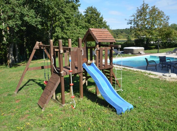 A wooden play structure with a slide, a hot tub, and outdoor seating by a pool. - Forest Breeze Retreat in Zminj (Sveti Petar u Sumi)