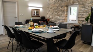 A dining area with a stone wall, a wooden table set for four, and black chairs.