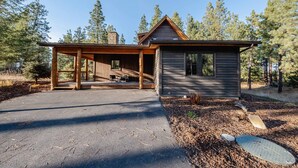 A cabin with a covered porch, a small attached shed, and a paved driveway. - Wilderness Club Cabin – Sleeps 7 (Eureka)
