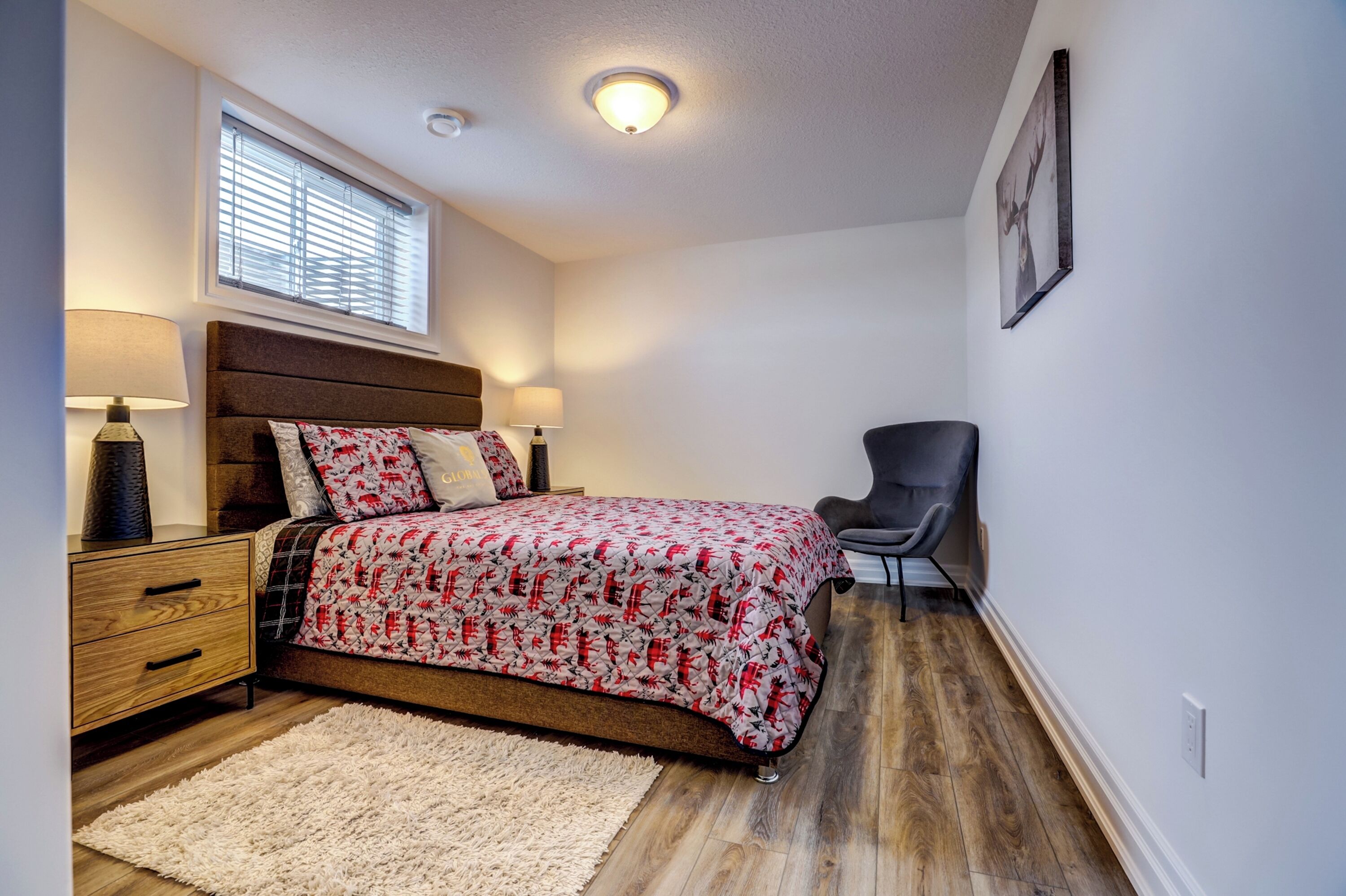 A bedroom with a bed, bedside tables, a chair, a window, and a ceiling light.