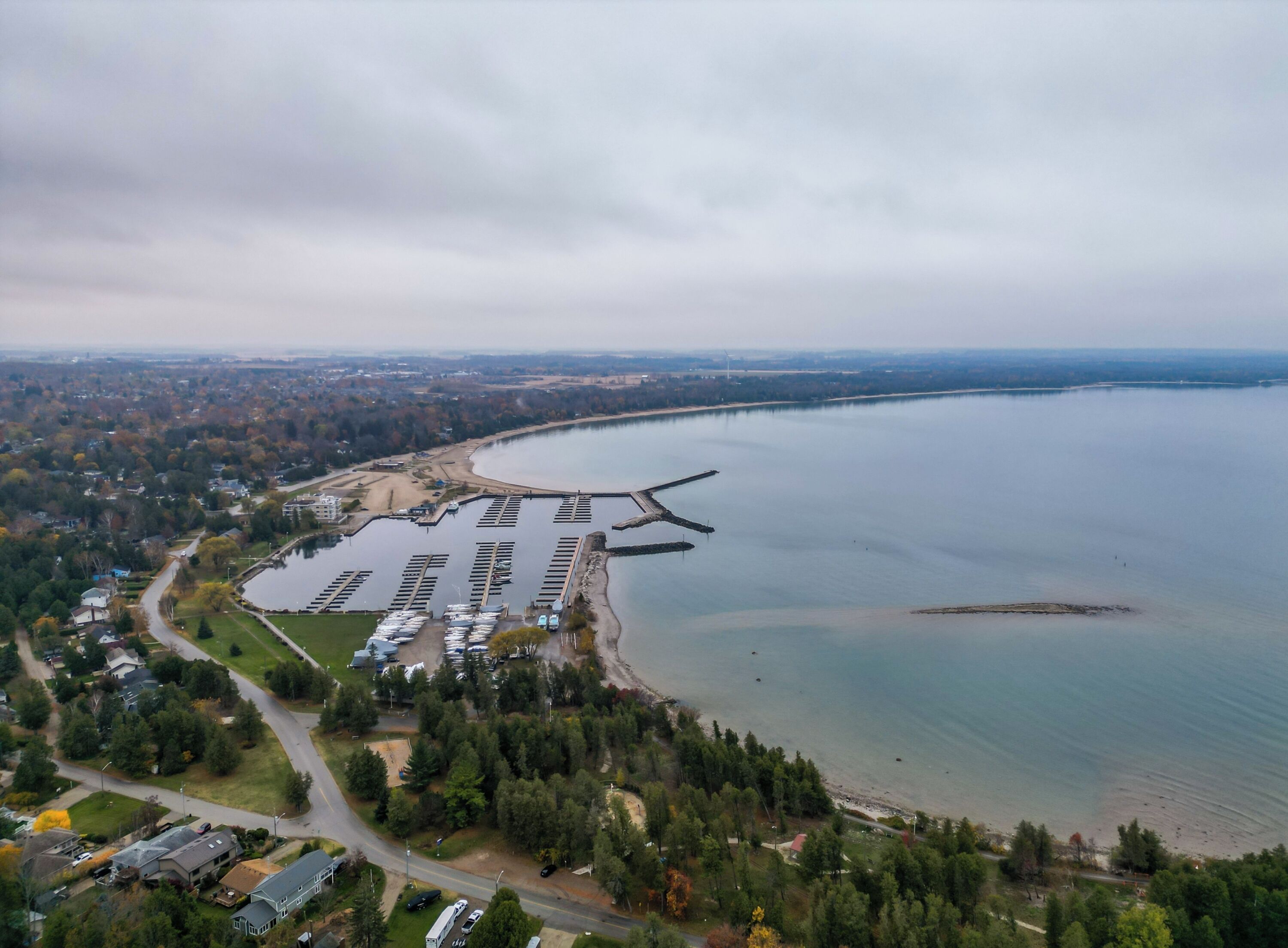 Luchtbeeld van een jachthaven met steigers en boten, omgeven door woonwijken en een groot wateroppervlak.