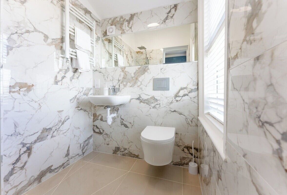 A bathroom with marble walls, a white sink, and a toilet.