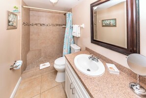 Un baño con ducha, inodoro, lavabo y un espejo grande.