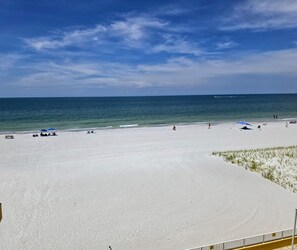 Ein weiter Sandstrand mit wenigen Sonnenschirmen und freiem Blick auf das Meer.