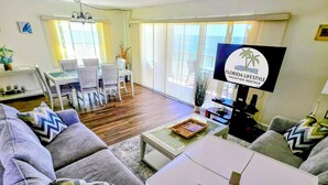A modern living room with grey sofas, a white coffee table, and a TV displaying 'Florida Lifestyle Vacation Rentals'.