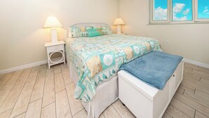 A bedroom with a bed, bedside tables, and a window.