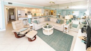 A modern living room with a sectional sofa, a rocking chair, a coffee table, and a dining area with chairs and a table.