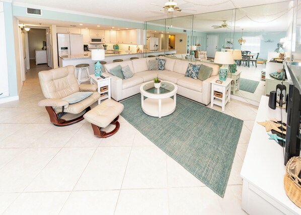 Een moderne woonkamer met een hoekbank, een schommelstoel, een salontafel en een eethoek met stoelen en een tafel.