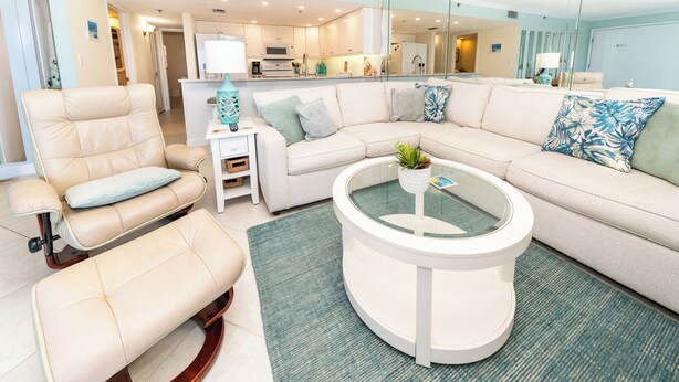 A modern living room with a beige sectional sofa, a rocking chair, and a glass coffee table.