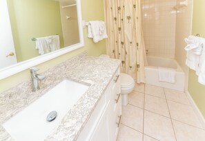 A bathroom with a marble sink, white toilet, and bathtub.