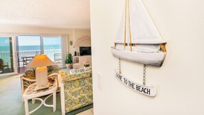 Un salón con vista al mar, una decoración con un velero y un cartel que dice 'GONE TO THE BEACH'.