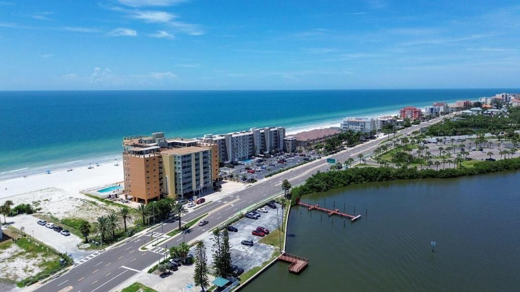 Un hôtel situé sur la côte, avec vue sur la plage, un parking et un port de plaisance.