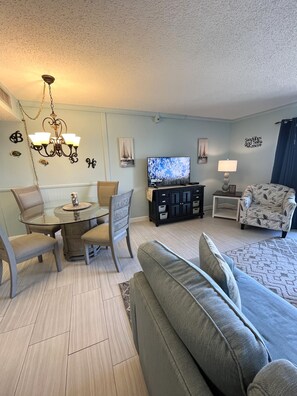 A living room with a dining table, sofa, TV, and decorative wall art.