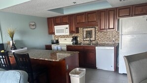 Una cocina compacta con armarios de madera, microondas, cafetera y lavavajillas.