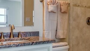A bathroom with a marble sink, a toilet, and a shower area.