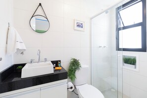 A modern bathroom with a black countertop sink, a toilet, and a glass shower enclosure. - Casa com 2 suítes AC Higienópolis (São Paulo)