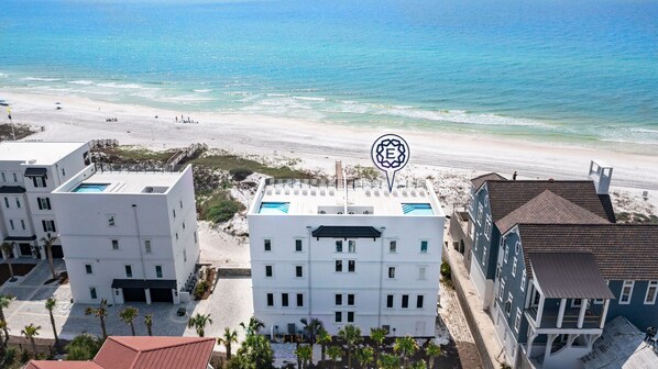 A beachfront hotel with a pool, multiple buildings, and a clear view of the ocean. - Azzurro Moon|Private Deeded Beach|Gulf Front Villa with Private Rooftop Pool (Seagrove Beach)