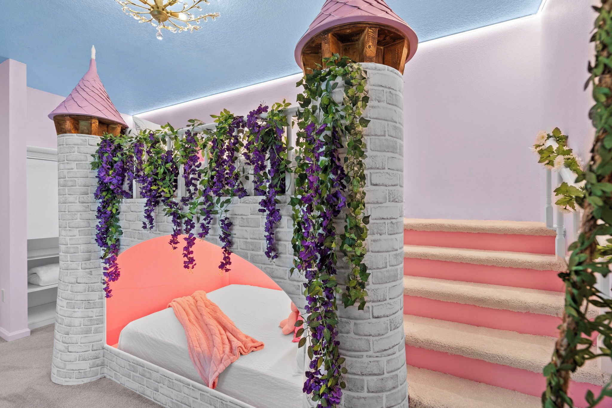 Ein schlossähnliches Schlafzimmer mit einem Bett, einer Treppe und einer Chandelüster.