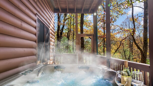 A hot tub with a wooden deck and a view of autumn trees. - Log Cabin, Lake, Hot Tub, Near Wineries & Hiking (Dahlonega)