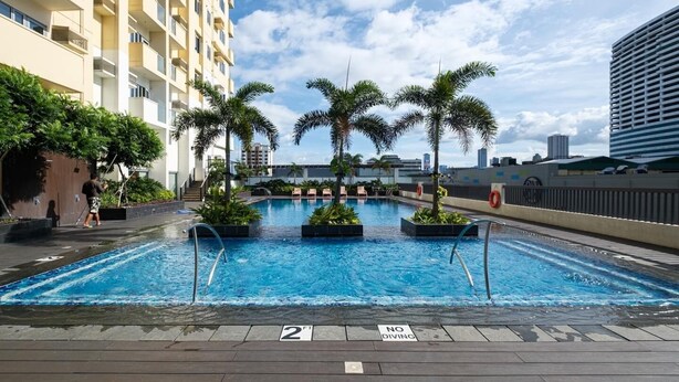A rooftop pool with palm trees, a 2 ft depth marker, and a no diving sign. - Skyline Stay in Araneta Cubao w/ Karaoke & Netflix  (Quezon City)