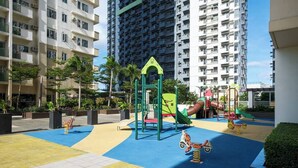 A playground with various play structures, surrounded by residential buildings. - Skyline Stay in Araneta Cubao w/ Karaoke & Netflix  (Quezon City)