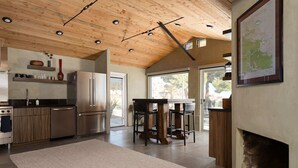Una cocina moderna con vigas de madera en el techo, electrodomésticos de acero inoxidable y un comedor con un amplio ventanal.