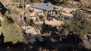 Una propiedad residencial con piscina, mobiliario exterior y un patio cubierto.