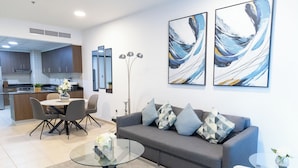 A modern living room with a grey sofa, a glass coffee table, and abstract art on the wall. - HAPPY SEASON I Elite Tower Dubai Marina (Dubai)