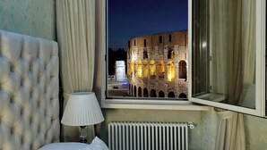 Ein Zimmer mit Blick auf das Kolosseum bei Nacht.