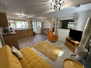 Uma sala de estar moderna com sofá, televisão e área de jantar com mesa e cadeiras.